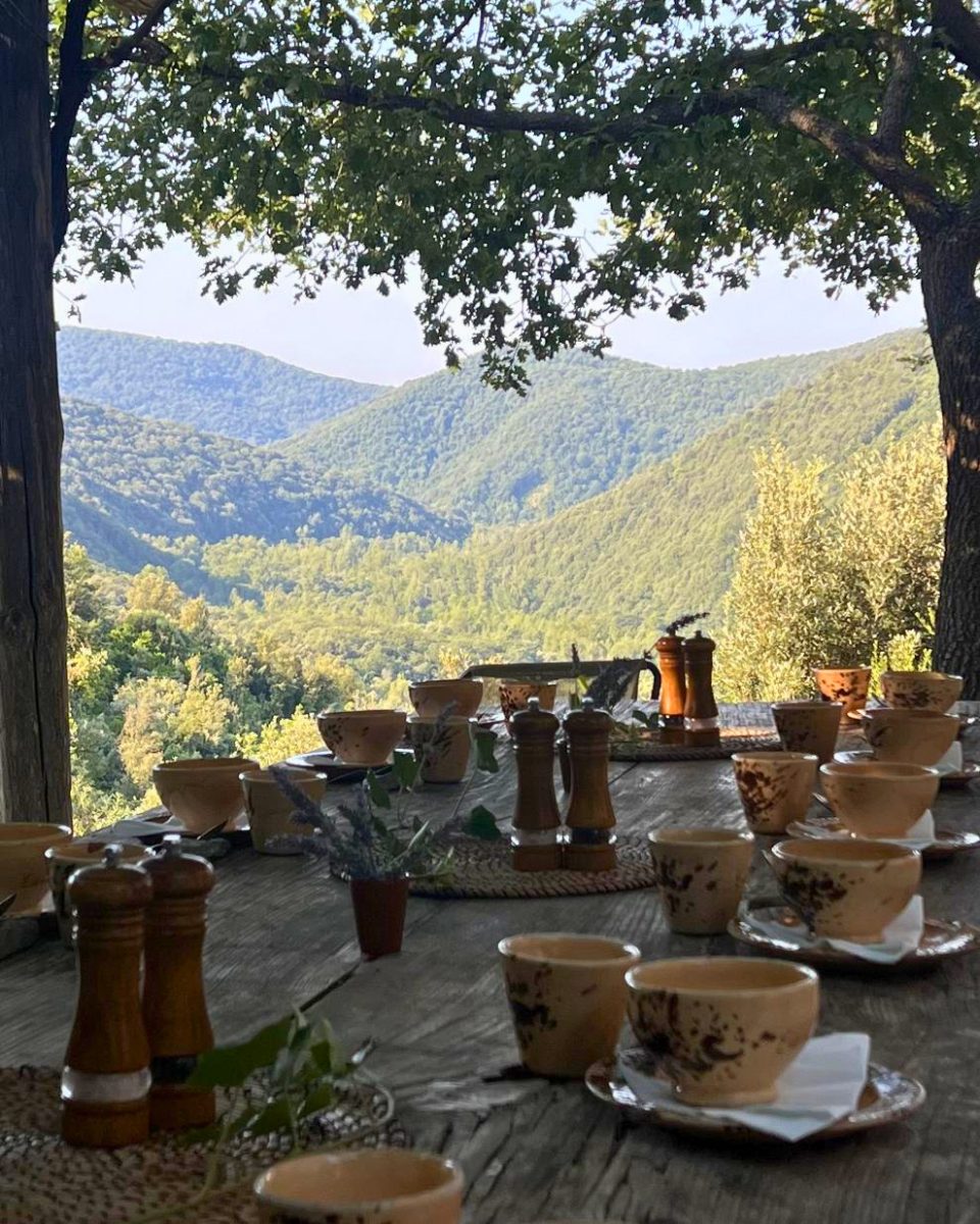 Tazze in ceramica su un tavolo all'aperto affacciato sui boschi