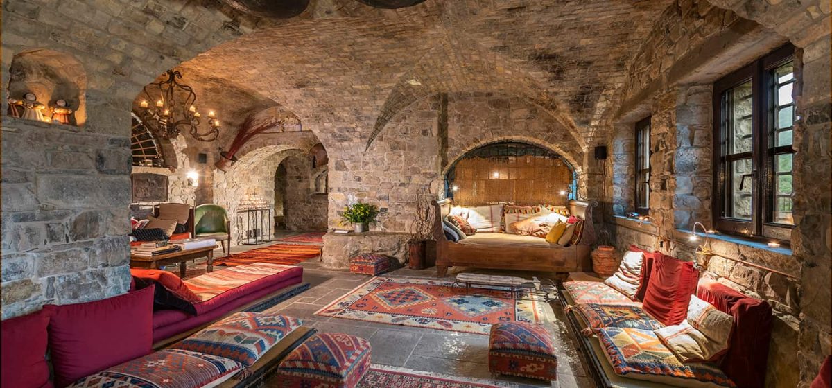 Salone voltato in pietra con tappeti kilim, divani bassi e cuscini colorati