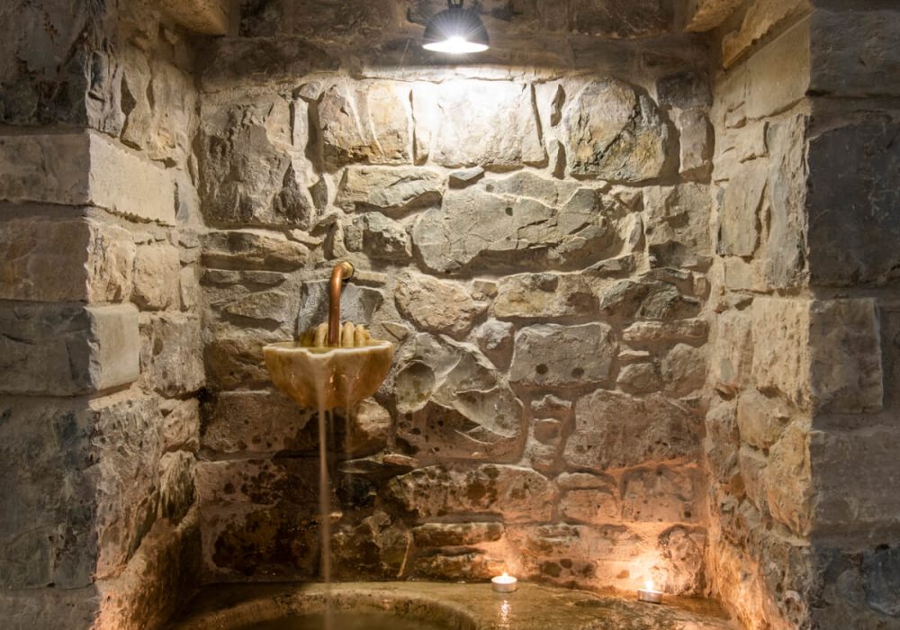 Fontana in pietra in una nicchia illuminata dalle candele