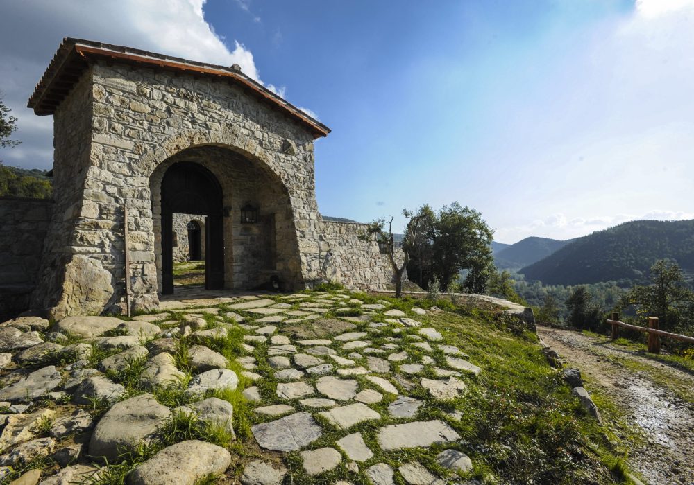 Camminamento acciottolato tra le mura di Eremito con vista sulla valle