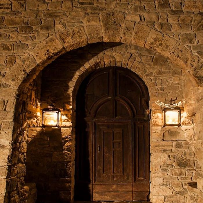 Portone in legno sotto l'arco in pietra illuminato da due lanterne