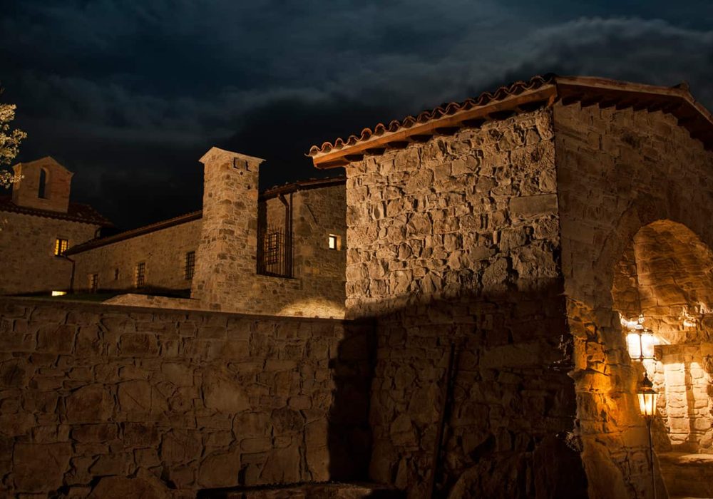 Eremito di notte con le mura in pietra illuminate dalle lanterne