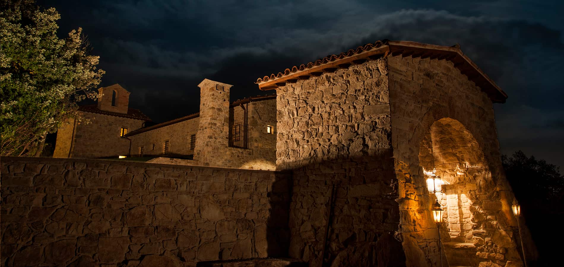 Eremito di notte con le mura in pietra illuminate dalle lanterne