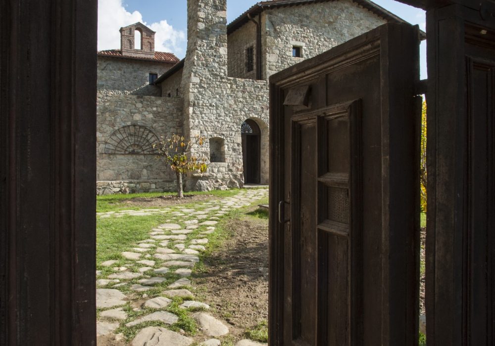 Corte acciottolata di Eremito con campanile a vela e portone in legno aperto