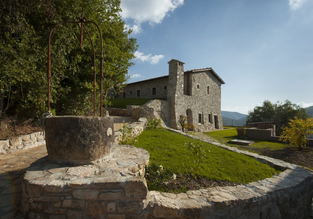 Esterno in pietra di Eremito con prato e arco in ferro battuto