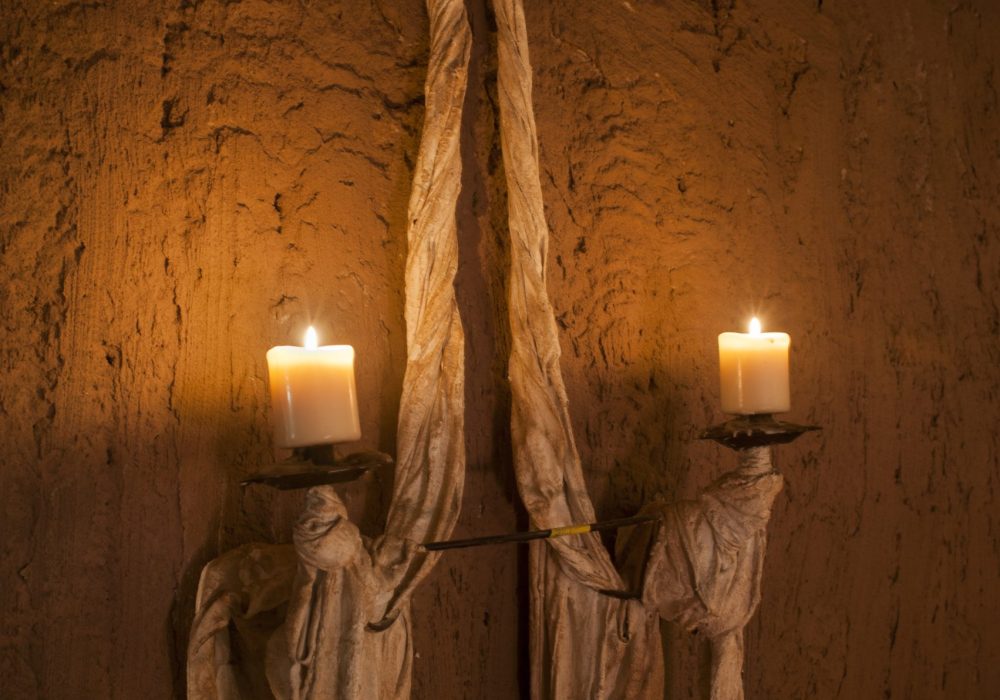 Candele accese su parete in pietra, unica illuminazione delle sere a Eremito