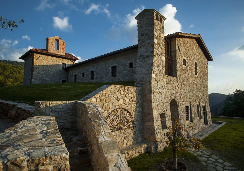 Veduta esterna di Eremito con prato, torre in pietra e cielo nuvoloso