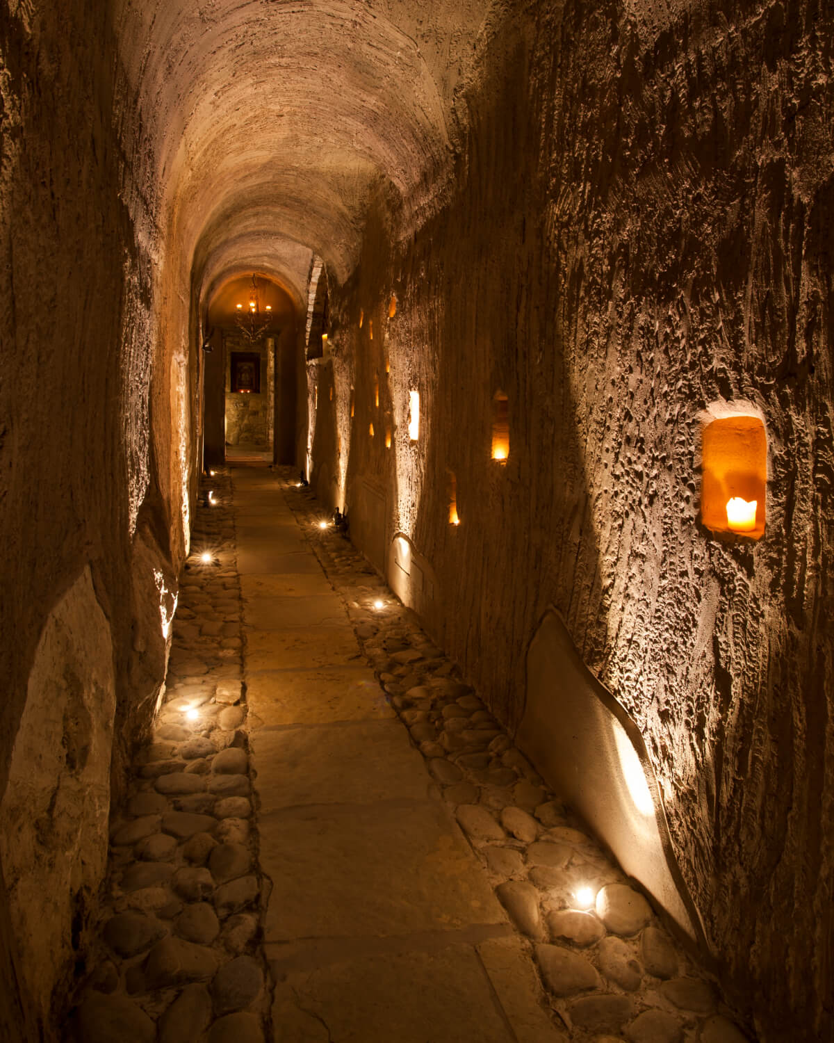 Long vaulted corridor lit only by candles and lanterns