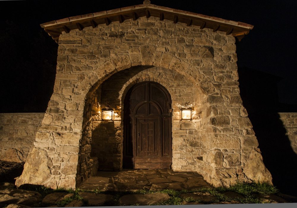 Portone in legno ad arco illuminato da due lanterne