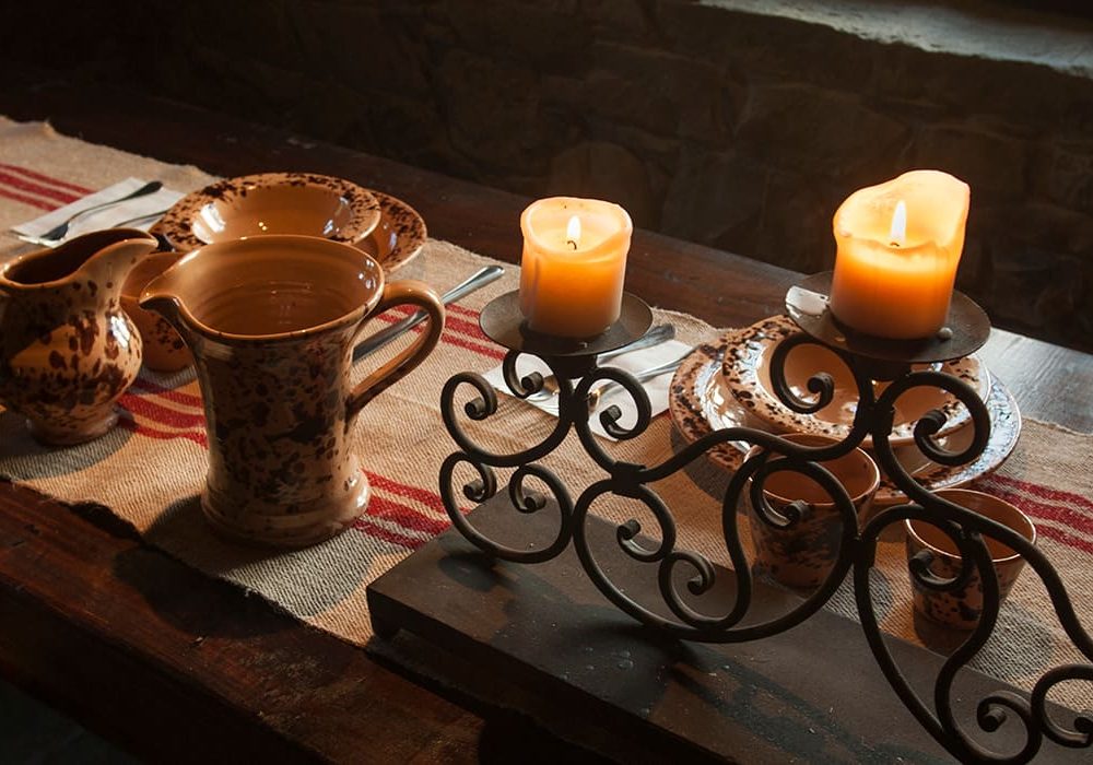 Tavola con brocca in rame, candele accese e runner a righe