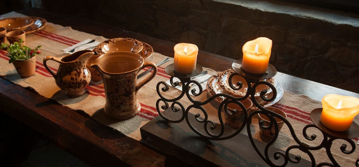 Tavola con brocca in rame, candele accese e runner a righe