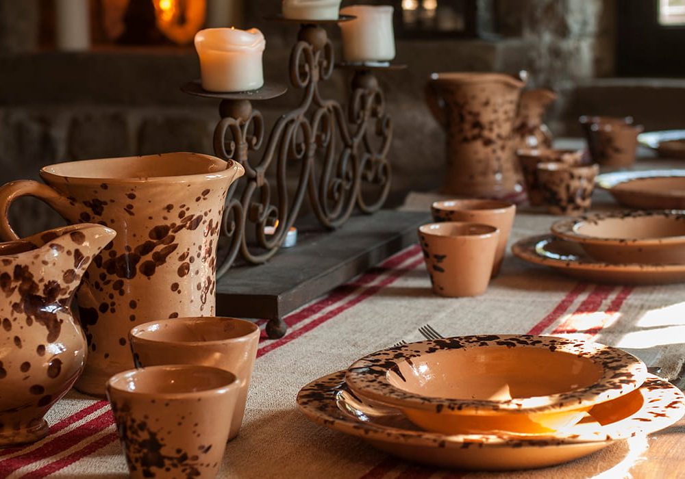Tavolo del refettorio con brocche e piatti in ceramica artigianale