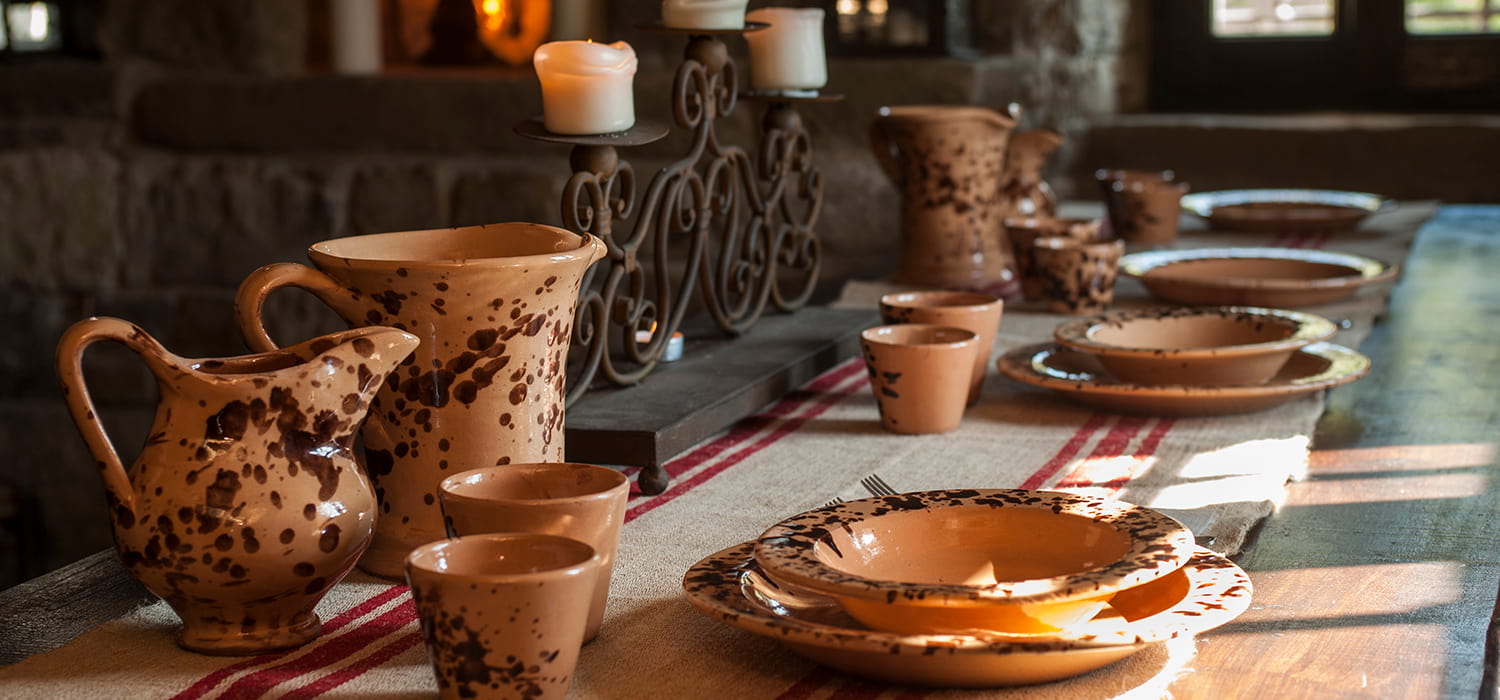Tavolo del refettorio con brocche e piatti in ceramica artigianale