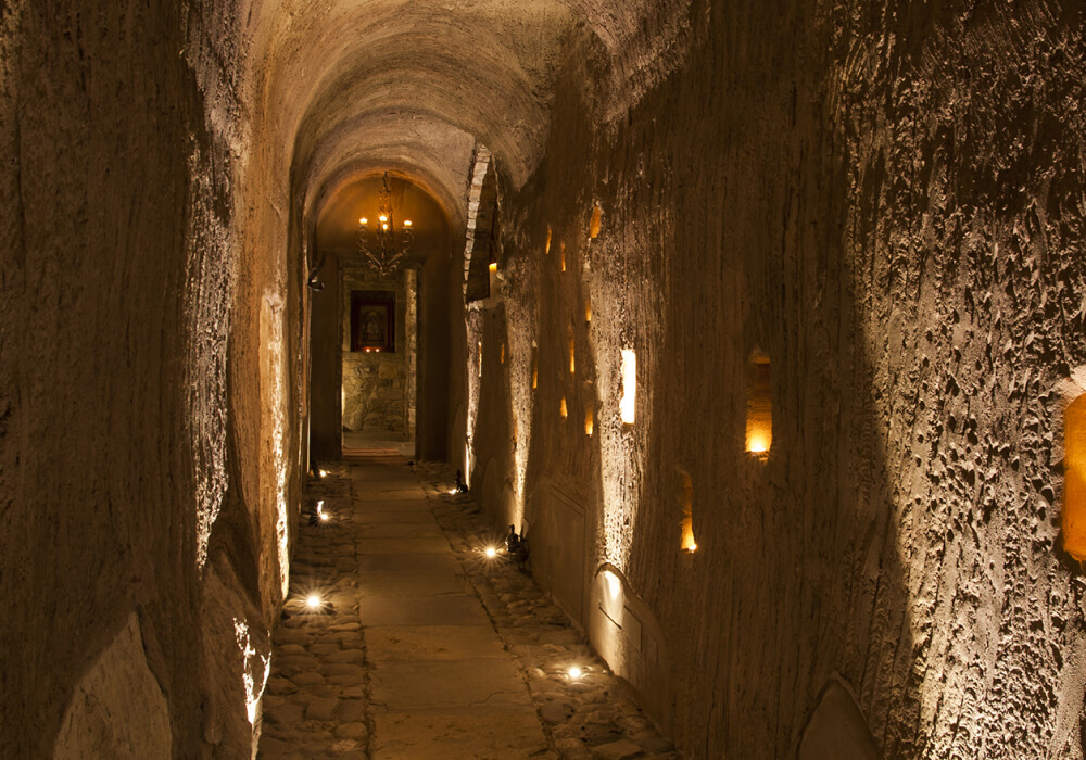 Lungo corridoio di Eremito illuminato solo da candele