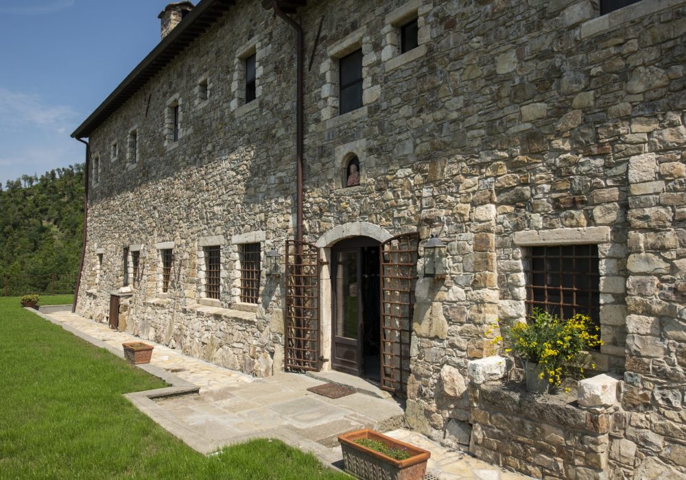 Facciata in pietra di Eremito con ingresso ad arco e prato