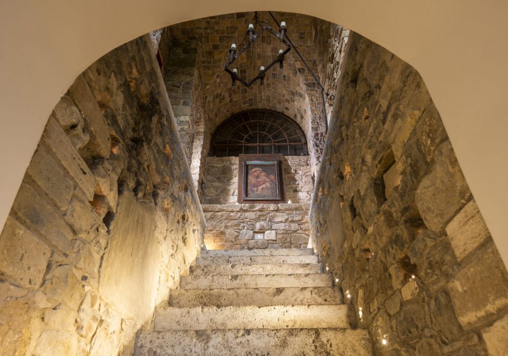 Scalinata voltata con lampadario in ferro e icona sacra sul fondo