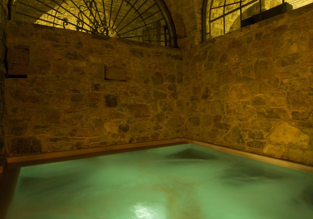 Piscina interna in pietra illuminata dalla luce calda delle candele