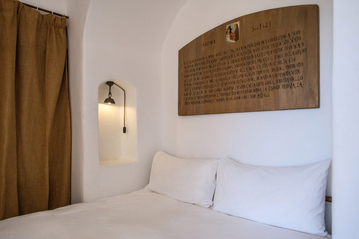 Celluzza Priore, letto con biancheria bianca, tenda di juta e tavola dipinta dedicata a Maria Egiziaca